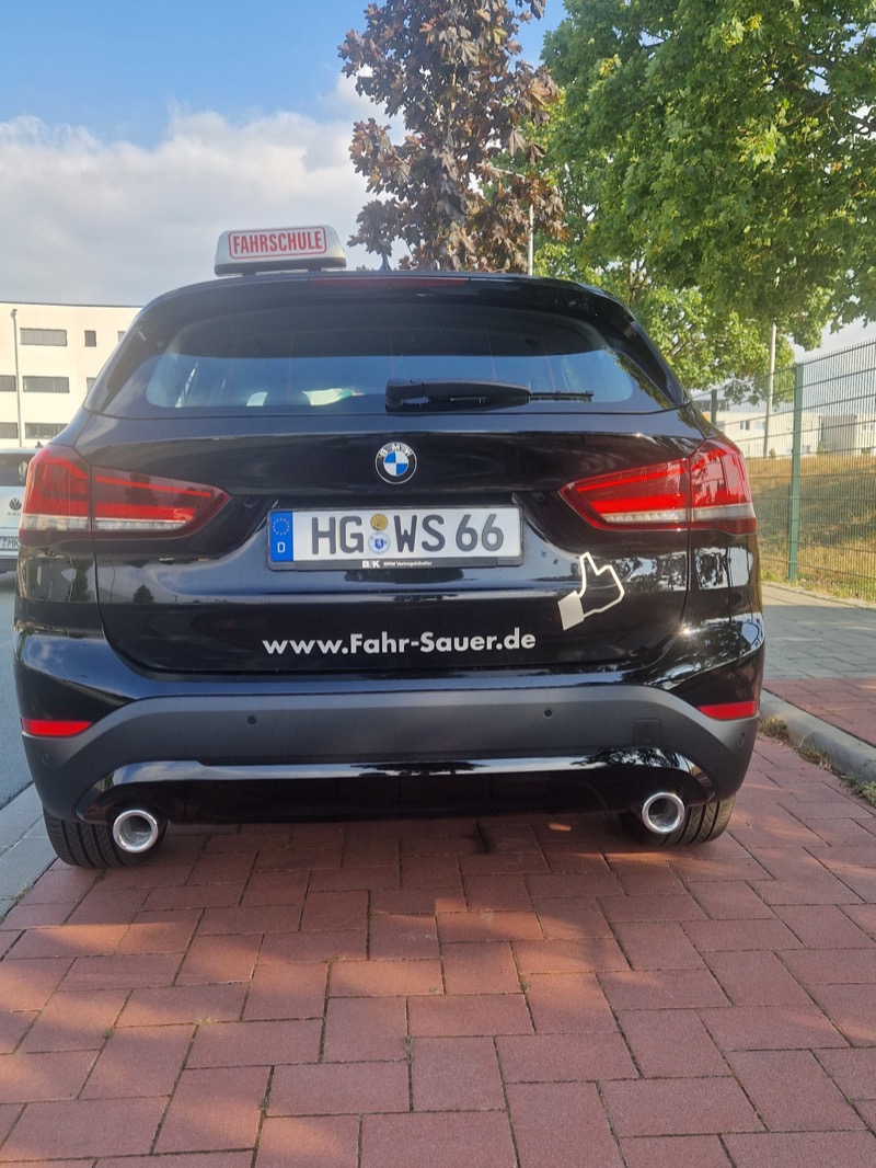 Heckansicht des BMW X1 der Fahrschule Willi Sauer mit Fahrschulschild