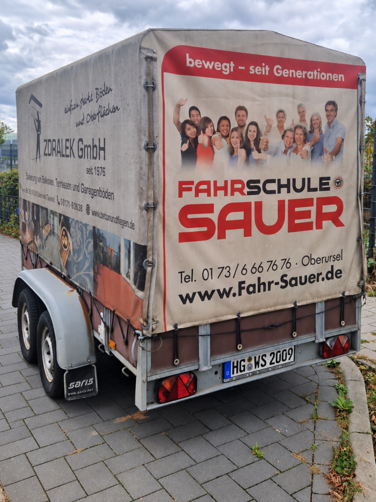 KI-bearbeitetes Foto: Pkw-Anhänger mit Werbeplane der Fahrschule Willi Sauer